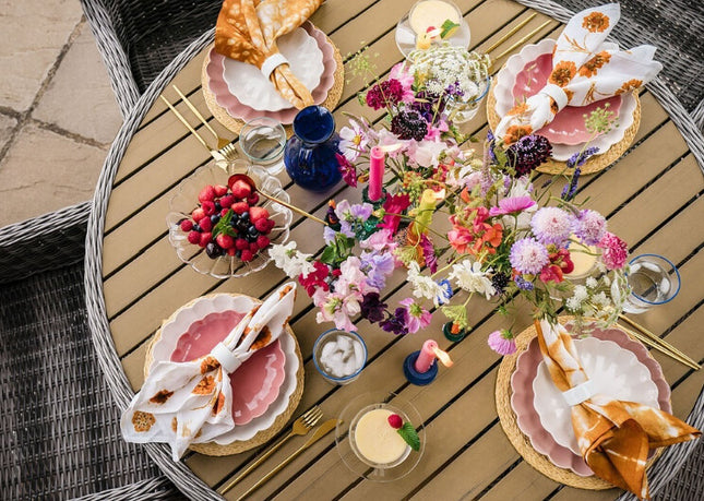 Decorative table setting with flowers, plates, and glasses on a wooden table.