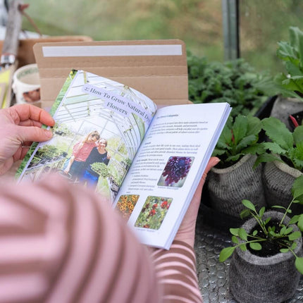 Person reading a book in a greenhouse with plants around