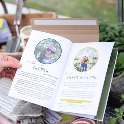 Person holding an open book with garden-themed pages, surrounded by gardening tools and plants.