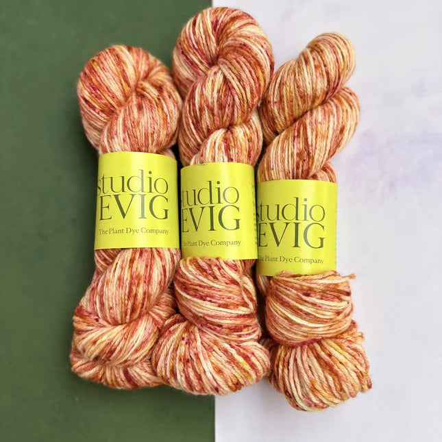 Three skeins of yarn with 'Studio EVIG' labels on a green and white background