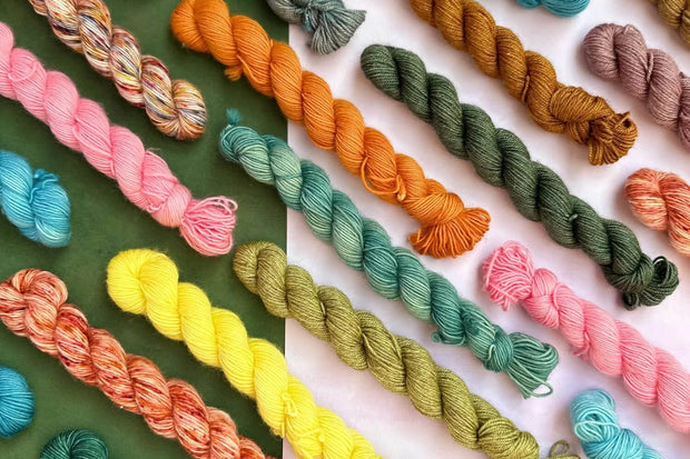 Colorful yarn skeins arranged in a grid on a white background